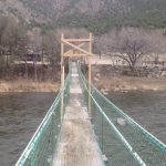 Suspension bridge leading to private tent sites across the river at Sweetwater River Ranch in Texas Creek, CO